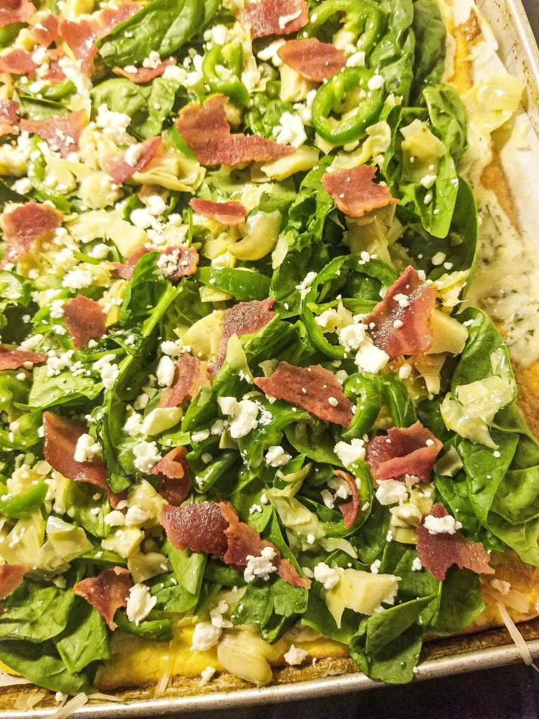 spinach alfredo pizza uncut on a sheet pan