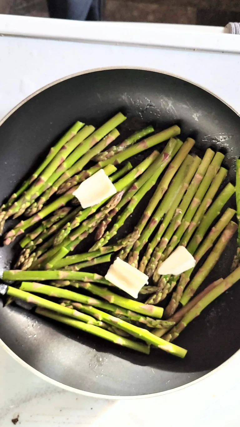 Frying asparagus with garlic butter on top.